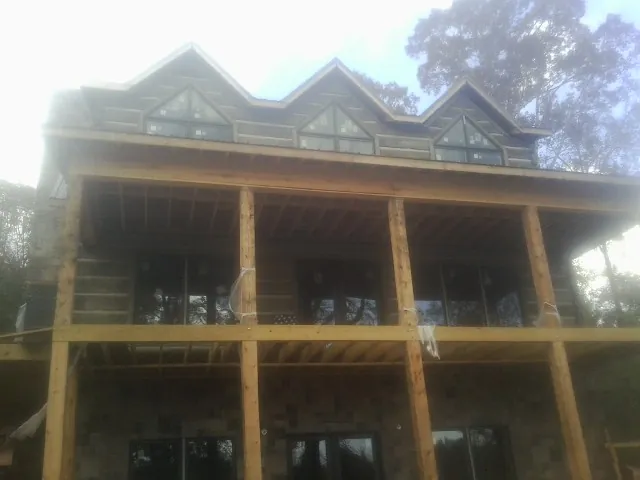 Dormers and porch framing on a large log home under construction — Roof Coating work by our crew in Belle Plaine
