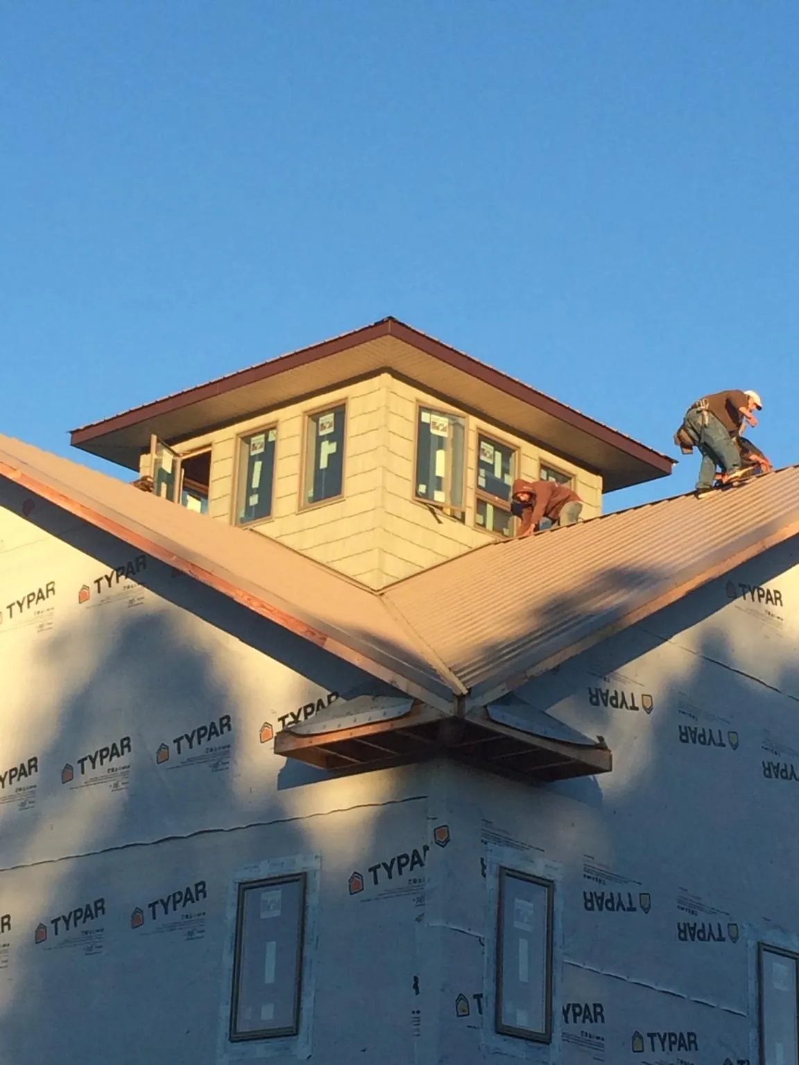 Roofers working around a rooftop cupola on a new metal roof at sunset — Roof Waterproofing in Belle Plaine by Roofing Brothers